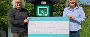 Hjertestarteren, som Sol og Strand har doneret, er nu opsat centralt i sommerhusområdet ”Lille Norge” i Saltum. Her overrækker bureauchef Julia Spiess Woldsgaard-Iversen det synlige bevis på donationen til kassereren for ”Grundejerforeningen Lille Norge”, Inge Lise Holm. 